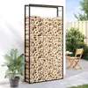 A vidaXL firewood rack filled with firewood, placed on a patio next to a white wall and a potted plant. A chair and table are visible in the background. Anteprima dell’immagine prodotto