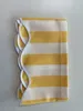 A folded yellow and white striped awning valance with a scalloped edge and white trim, laid flat on a white surface. Produktbild-Vorschau