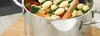 A close-up shot of a pot of gnocchi with vegetables, placed on a wooden cutting board. Produktbild-Vorschau