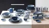A collection of blue and white patterned tableware is arranged on a white surface and a light brown tablecloth. Produktbild-Vorschau