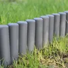 A row of dark gray garden edging posts is installed in the grass along a garden path. Produktbild-Vorschau