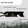 A close-up marketing image of a black multitool with various features labeled in German, set against a blurred background of a forest. Produktbild-Vorschau