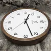 A wooden wall clock is shown on a textured wooden surface. Voir les images du produit