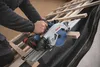 A person is using a cordless circular saw to cut wood on a roof. Produktbild-Vorschau