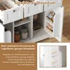 A close-up view of a white kitchen cart with open drawers and shelves, showcasing storage solutions and some food items. The image is overlaid with German text describing its features. Produktbild-Vorschau