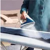 A person is ironing a pair of denim pants on an ironing board, with steam coming from the iron. Produktbild-Vorschau