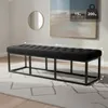 A black upholstered bench with a metal frame is placed on a rug in a room with a painting on the wall and a round mirror. Náhled obrázku produktu