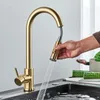 A person's hand is holding a gold kitchen faucet sprayer over a sink. Anteprima dell’immagine prodotto