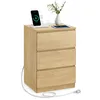 A wooden nightstand with three drawers, featuring electronic devices on top. A power cord is visible, plugged into the side of the nightstand. Náhled obrázku produktu