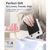 A person is holding a white and black electronic device over a white shopping bag. There are gift boxes on a side table in the background. Produktbild-Vorschau