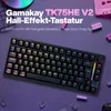 A black Gamakay TK75HE V2 keyboard is displayed on a purple background, surrounded by small pink building blocks and other decorative elements. Produktbild-Vorschau