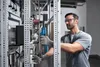 A man is working on an electrical panel with a tool. Produktbild-Vorschau