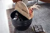A round storage table with a wooden lid is placed on a rug next to a leather notebook. Voir les images du produit