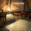Inside a tent, a green emergency radio with a light is placed on a sleeping bag next to a map. A thermos is also visible. Produktbild-Vorschau