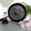 A cast iron pan with oil in it, a bottle of olive oil, and a kitchen towel. Produktbild-Vorschau