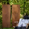 Two tall, rectangular metal screens with a rust-like finish stand in a grassy outdoor setting with trees in the background. A wooden chair with a furry throw and a pillow featuring a deer is placed in front of one of the screens. Náhľad obrázku produktu