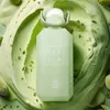 A perfume bottle is placed on a creamy, green background with pistachio pieces scattered around. Náhled obrázku produktu