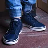 A person wearing blue jeans and dark blue Adidas sneakers. Náhľad obrázku produktu