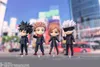 Four chibi-style anime figures are displayed in front of a blurred urban background. Produktbild-Vorschau