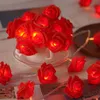 A string of red rose-shaped LED lights is arranged in and around a white teacup, creating a romantic and decorative atmosphere. Produktbild-Vorschau