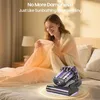 A woman is sitting on a bed, holding a blanket, with a mattress vacuum cleaner in the foreground. Produktbild-Vorschau
