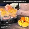 A person is placing orange slices into a food dehydrator, with a plate of fresh fruit in the foreground. Produktbild-Vorschau