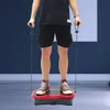 A person is standing on a vibration plate and holding resistance bands. Podgląd zdjęcia produktu