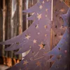 Close-up of a metal Christmas tree decoration with star cutouts, placed in front of a wooden wall. Voir les images du produit