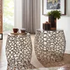 Two decorative side tables with intricate metal bases are shown in a living room setting. One table has a coffee cup and a muffin on it, while the other has decorative containers and a plant. Produktbild-Vorschau