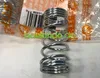 A close-up of a metal spring, with packaging and a barcode visible in the background. Produktbild-Vorschau