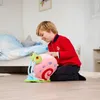 A young boy is playing with a plush toy snail in a bedroom. Voir les images du produit