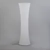 A tall, white, hourglass-shaped floor lamp with a fabric shade. Produktbild-Vorschau