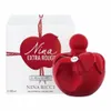 A product shot of a red apple-shaped perfume bottle and its packaging. Voir les images du produit
