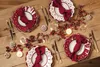 A festive Christmas table setting with plates, napkins, cutlery, candles, and decorative berries. Náhled obrázku produktu