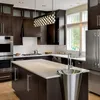 A modern kitchen with dark wood cabinets, stainless steel appliances, and a large kitchen island with a sink. Produktbild-Vorschau