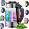 A collage of a glass electric kettle with LED lighting and various colored water displays, surrounded by smaller images of the same kettle with different colored water. A sprig of green tea leaves is in the foreground. Produktbild-Vorschau
