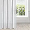 A white curtain hangs in front of a window with greenery visible outside. The floor is made of light-colored wood planks. Produktbild-Vorschau