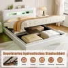 A white upholstered bed with storage is shown in a bedroom setting, with the storage compartment open and filled with items. Produktbild-Vorschau