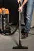 A person is vacuuming a floor with a wet/dry vacuum cleaner. Náhled obrázku produktu