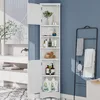 A white corner cabinet with open shelves and closed doors, filled with bathroom products, placed in a bathroom setting. Náhled obrázku produktu