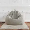 A light gray bean bag chair sits on a cream-colored rug in front of a white, ornate wall. Produktbild-Vorschau