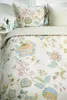 A close-up view of a floral patterned duvet cover and pillows on a bed. Produktbild-Vorschau