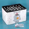 A beer crate with a Christmas-themed wrap, filled with bottles of beer, and a sheet of advent calendar stickers on the table. Produktbild-Vorschau
