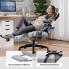 A woman is relaxing in a gaming chair with her feet up on a footrest, in a home office setting. Produktbild-Vorschau