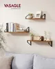 Three wooden shelves mounted on a light gray wall, decorated with books, a plant, a radio, and picture frames. A sofa is visible in the foreground. Náhled obrázku produktu