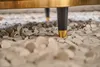 A close-up view of the legs of a piece of furniture resting on a bed of small, light-colored stones. Produktbild-Vorschau