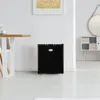 A black mini-fridge is placed on a white floor in a well-lit room, next to a wooden dining table. Voir les images du produit