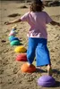 A child is playing on a beach, stepping on a line of colorful stepping stones. Voir les images du produit