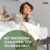 A woman is lying on a bed with a white duvet, smiling at the camera. A green overlay with text is present in the foreground. Produktbild-Vorschau