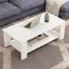 A white coffee table with a laptop and a vase on it, placed in a living room setting with a grey sofa and a patterned rug. Produktbild-Vorschau